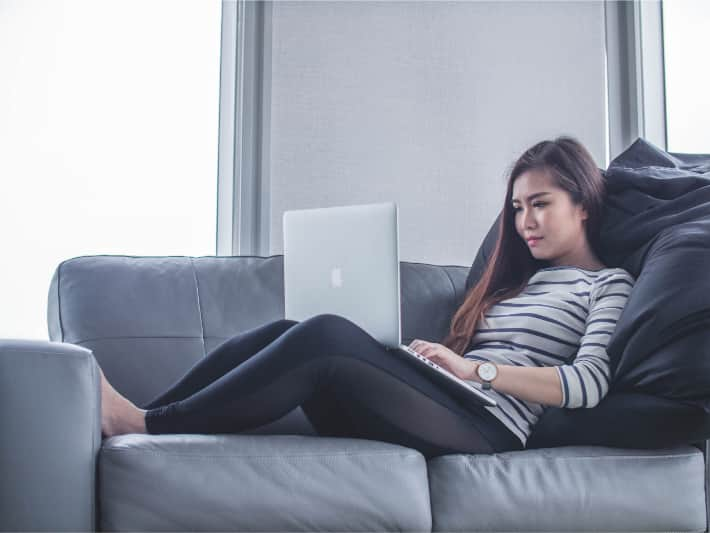 Mujer utilizando un equipo portátil en el sofá