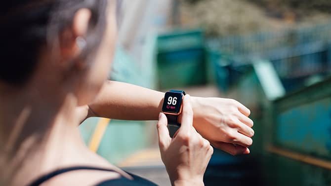 Una mujer utiliza una aplicación de fitness en su teléfono, que está sincronizada con su pulsera deportiva.